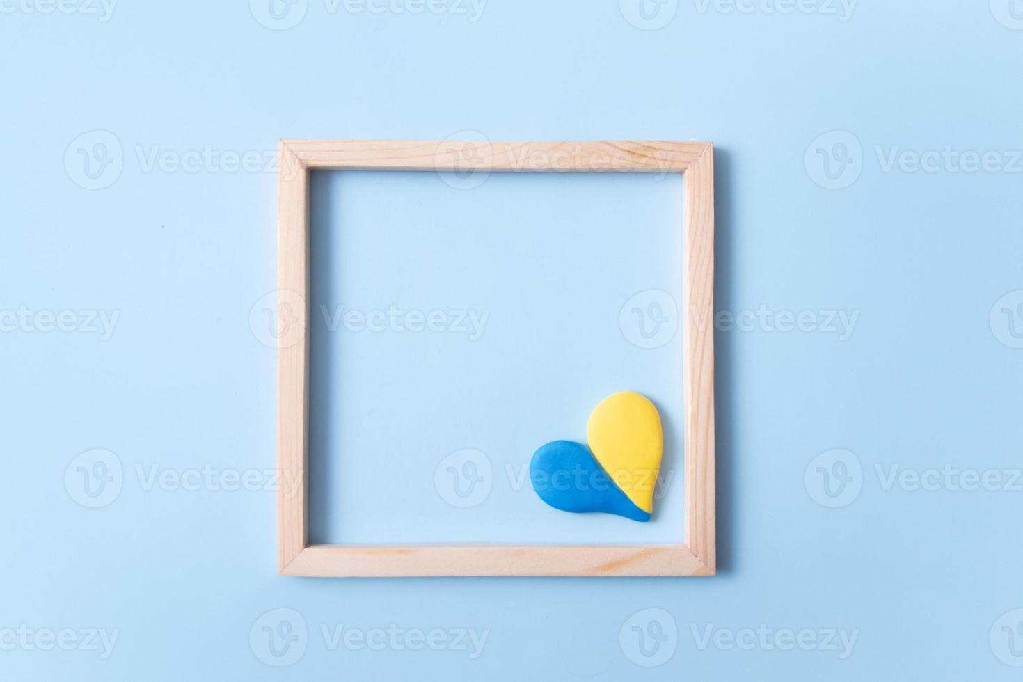 Heart shape yellow-blue color of the Ukrainian flag in a square wooden frame with copy space photo