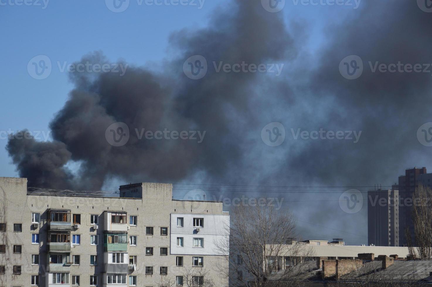 There is black smoke from a rocket or bomb explosion in a city during a war photo