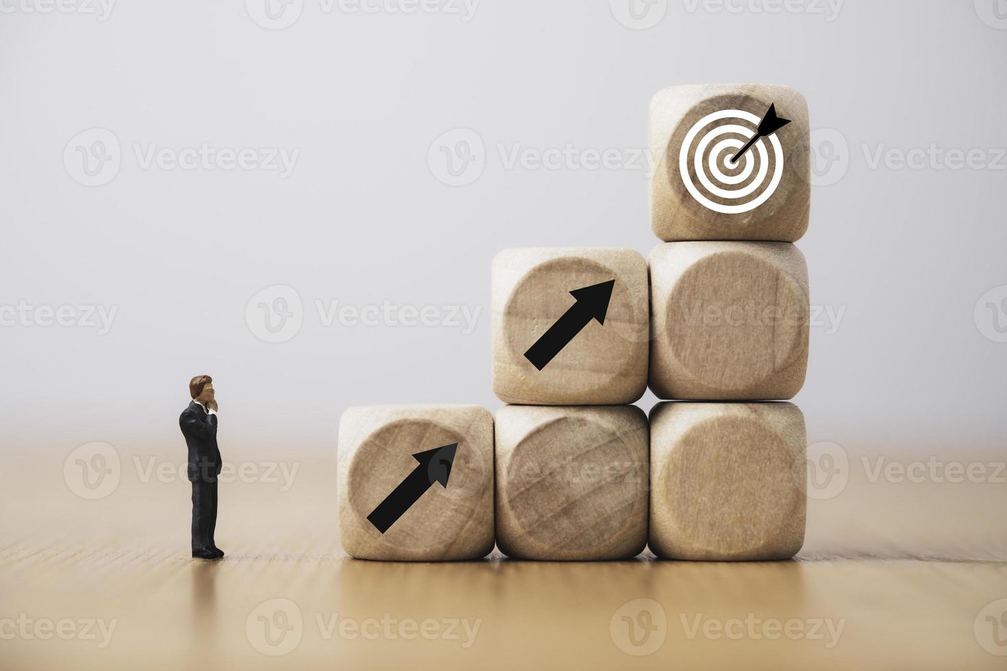 Businessman miniature figure standing and thinking consider increasing arrow with target board for setup business objective target concept. photo