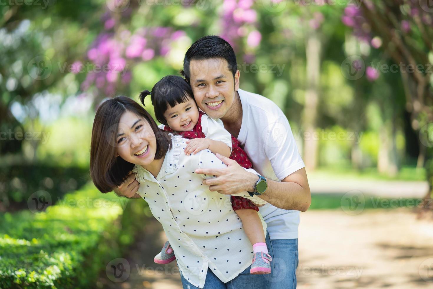 hermoso retrato de familia asiática sonriente y feliz. Padres tirando a su hija en el jardín. concepto de familia feliz. foto