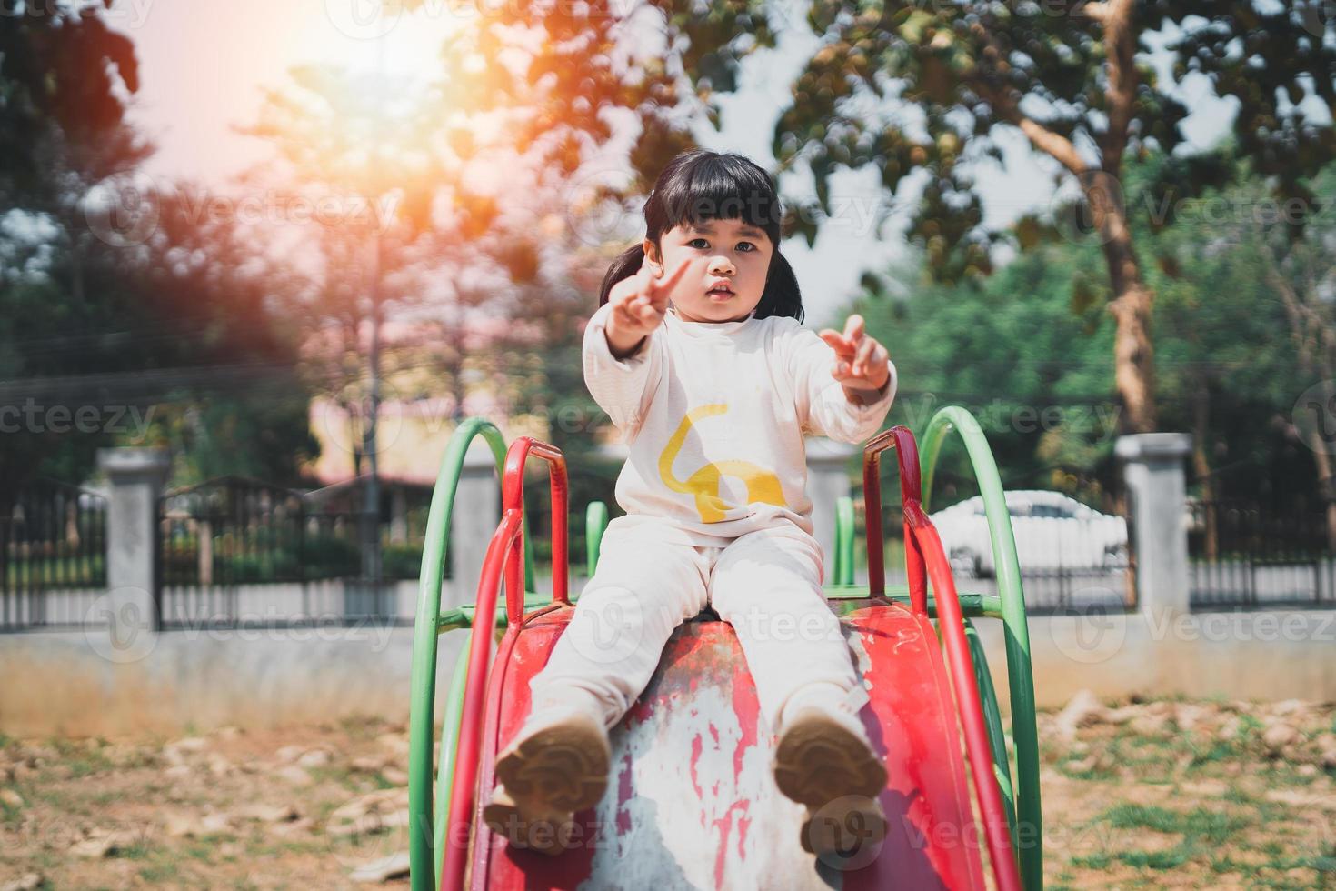 Cute asian girl play on school or kindergarten yard or playground. Healthy summer activity for children. Little asian girl climbing outdoors at playground. Child playing on outdoor playground. photo