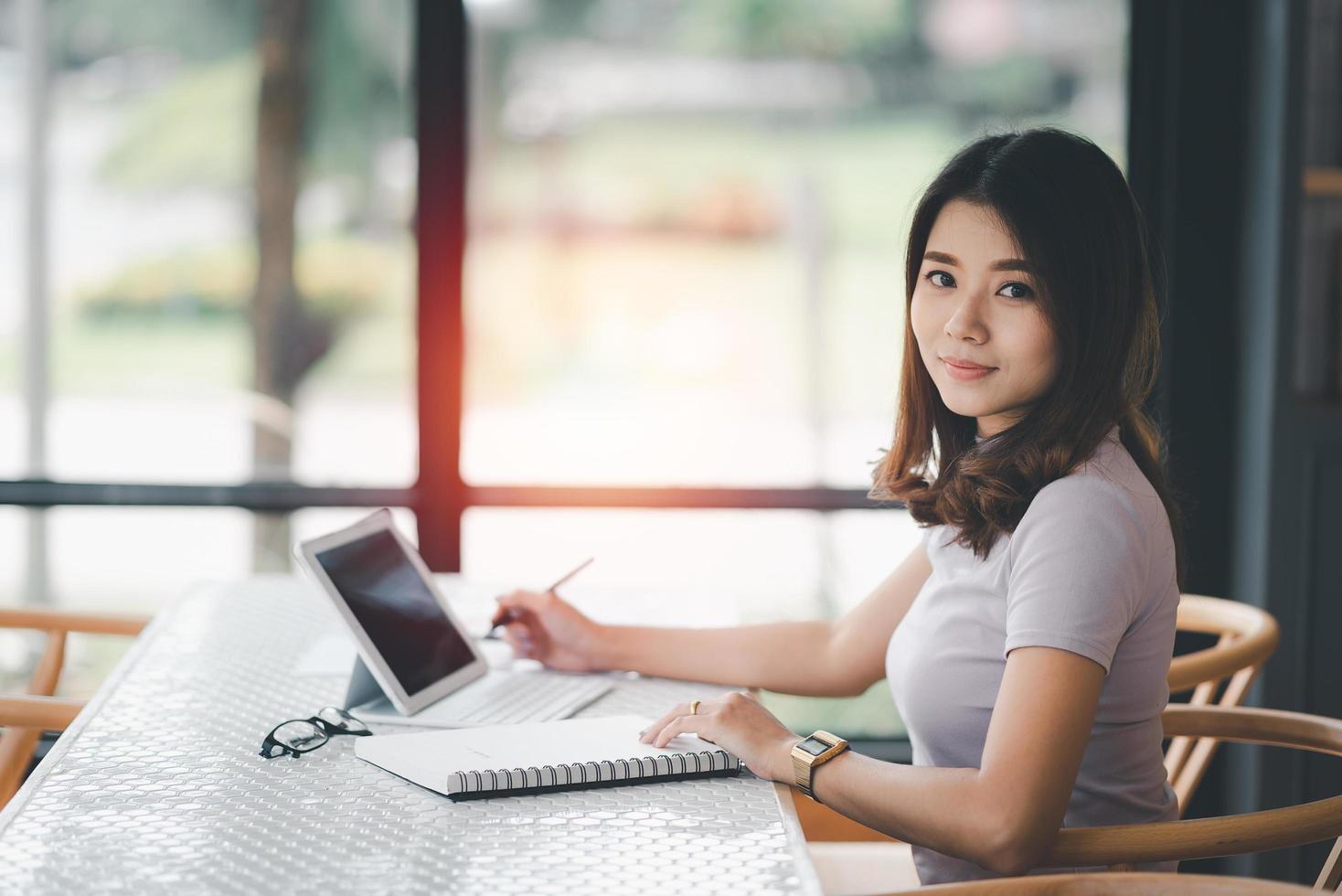 business woman working on laptop and using pen making notices in her notebook on wooden table with a cup of coffee. Business concept photo