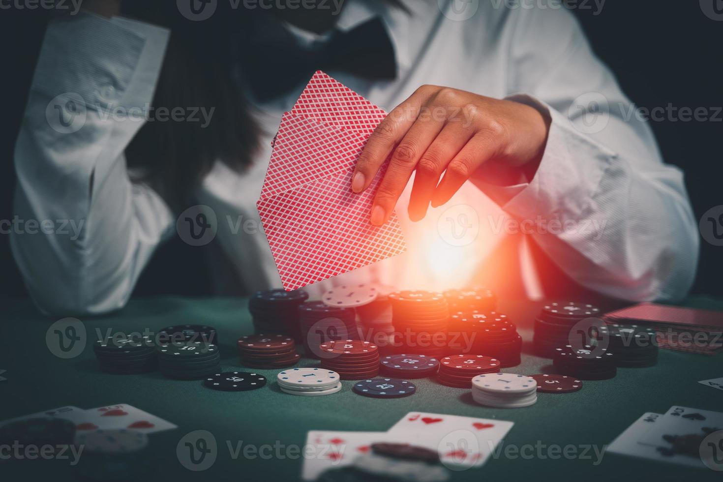 una distribuidora asiática o croupier baraja cartas de póquer en un casino al fondo de una mesa, como una mujer sosteniendo dos cartas de juego. casino, póquer, concepto de juego de póquer foto