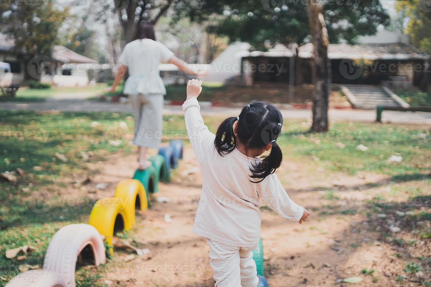 young asian mother playing with her baby on the playground. Mom and daughter. Cute baby daughter playing with mom happy funny family concept photo