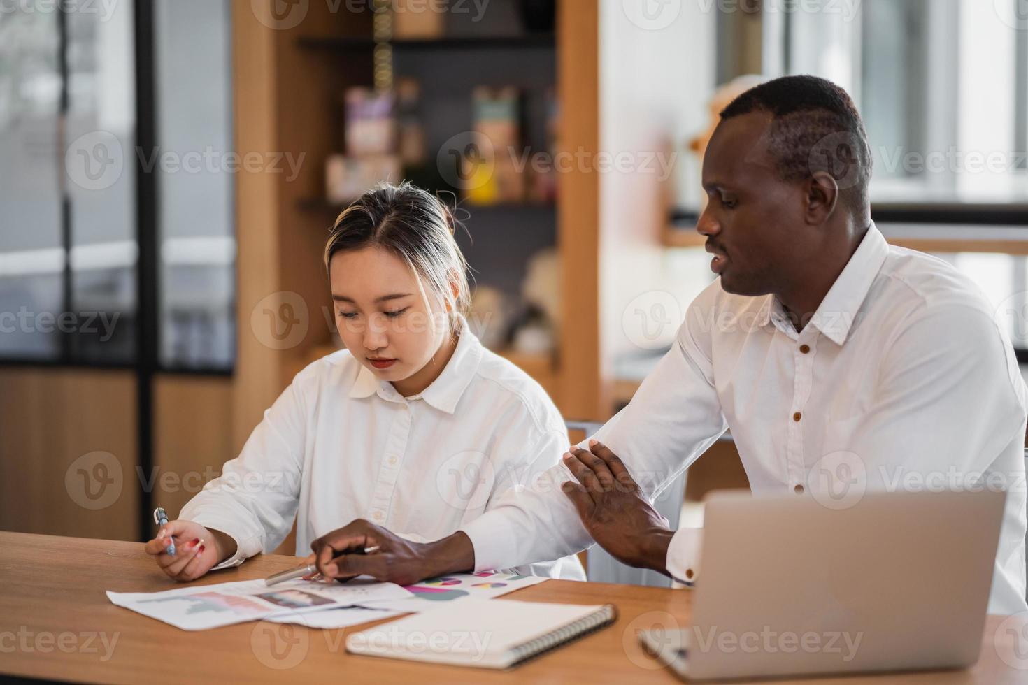 Two deference ethnic coworkers working together in modern cafe.Black business partners discussing new startup project. photo