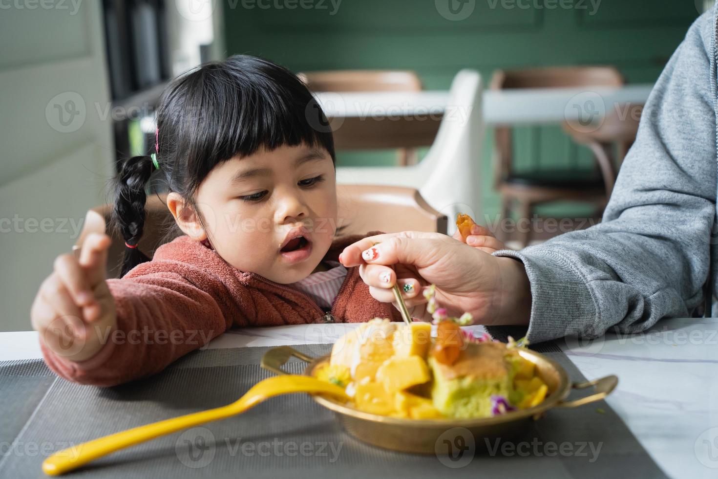 Mother feeding her baby daughter. Happy baby girl eating ice cream with mother in the living room. Family happy food toddler concept photo