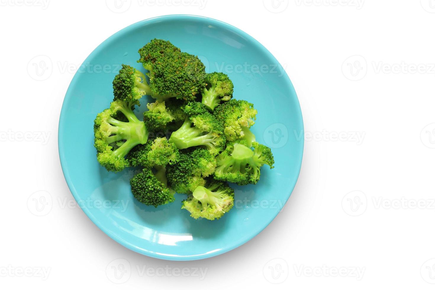 Boiled broccoli in a blue plate isolated on a white background with clipping path. Top view of Vegetables in a dish. Healthy food. photo