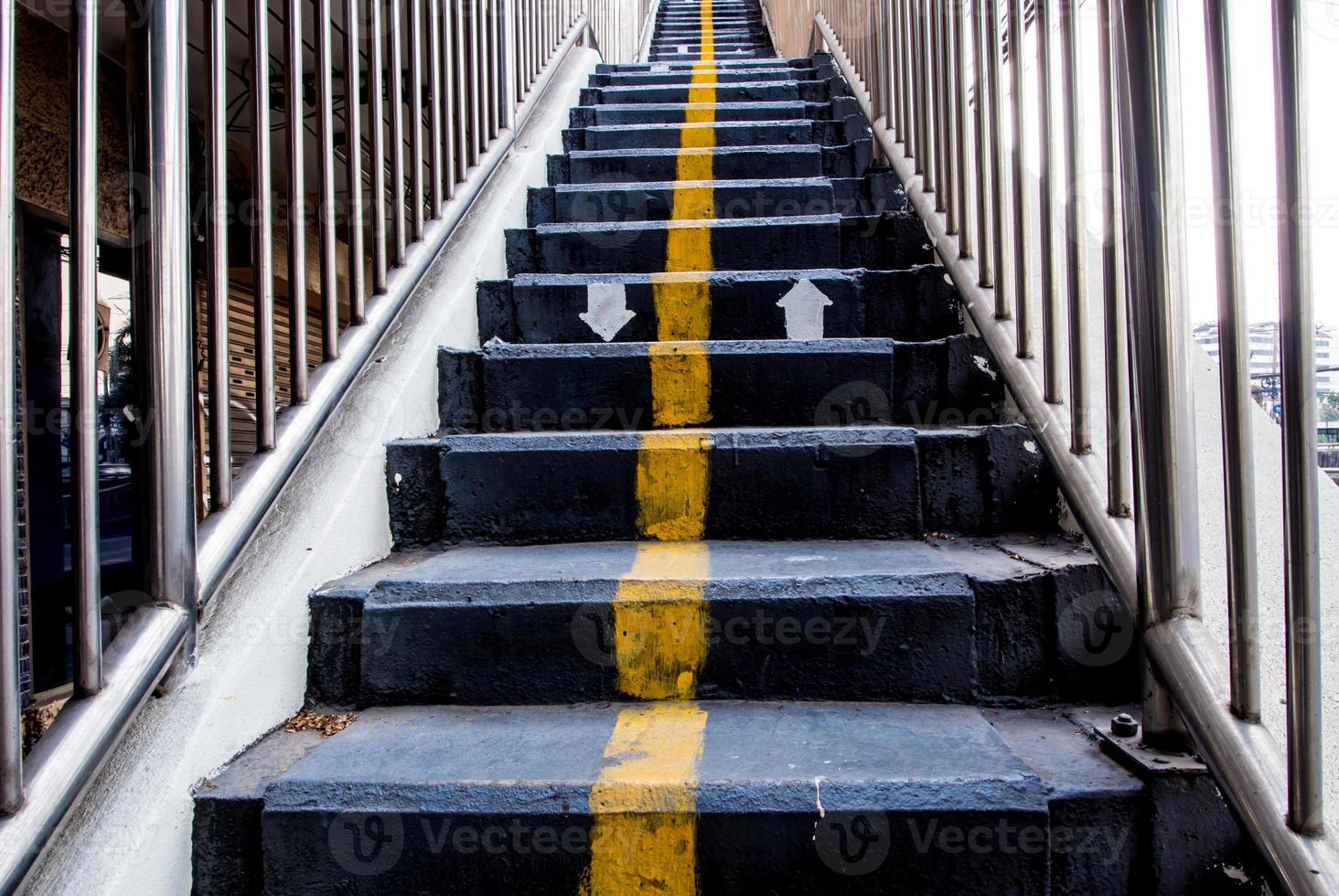 Yellow line and direction arrow painted on Concrete Stair of Overpass photo