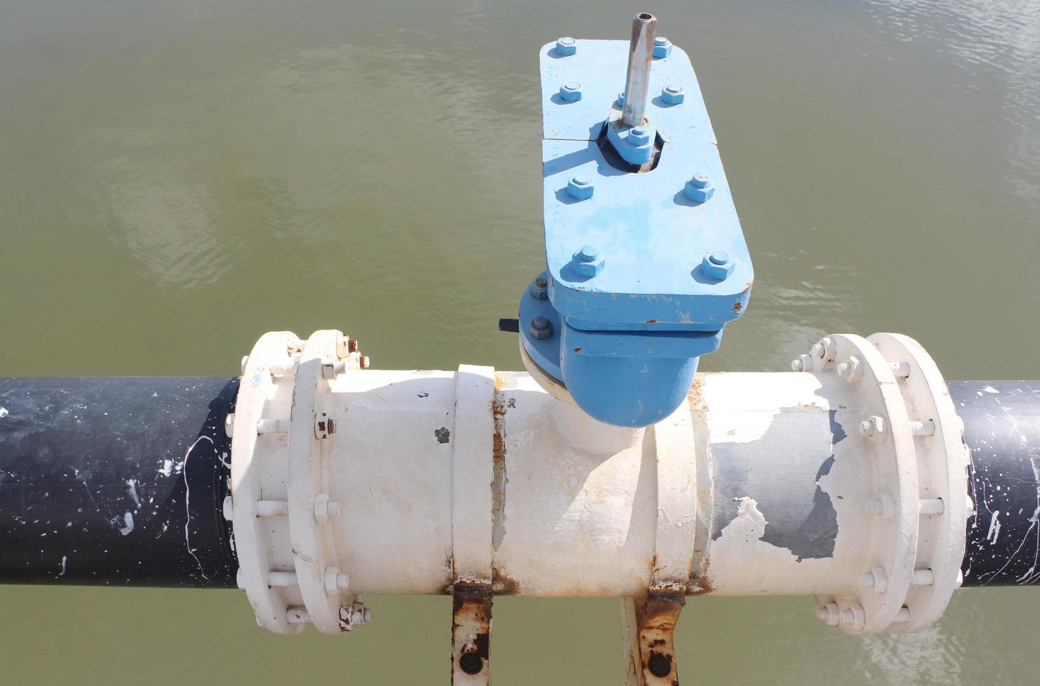 tubería de suministro de agua con conexiones de brida y pernos sobre el río. foto