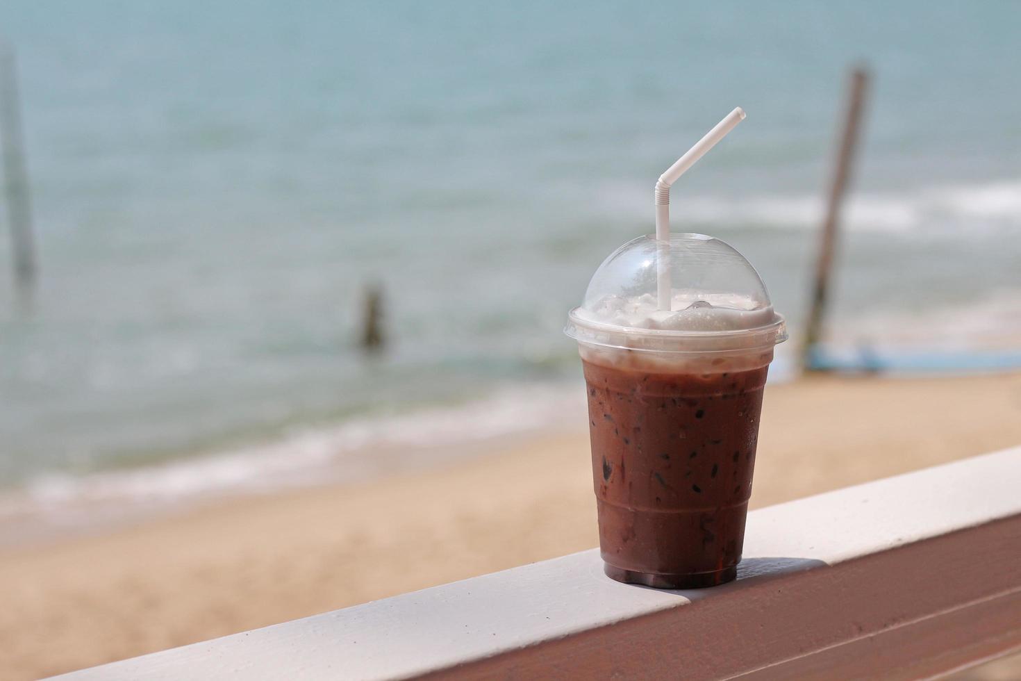 Iced chocolate drink in plastic glasses on a seaside table. photo