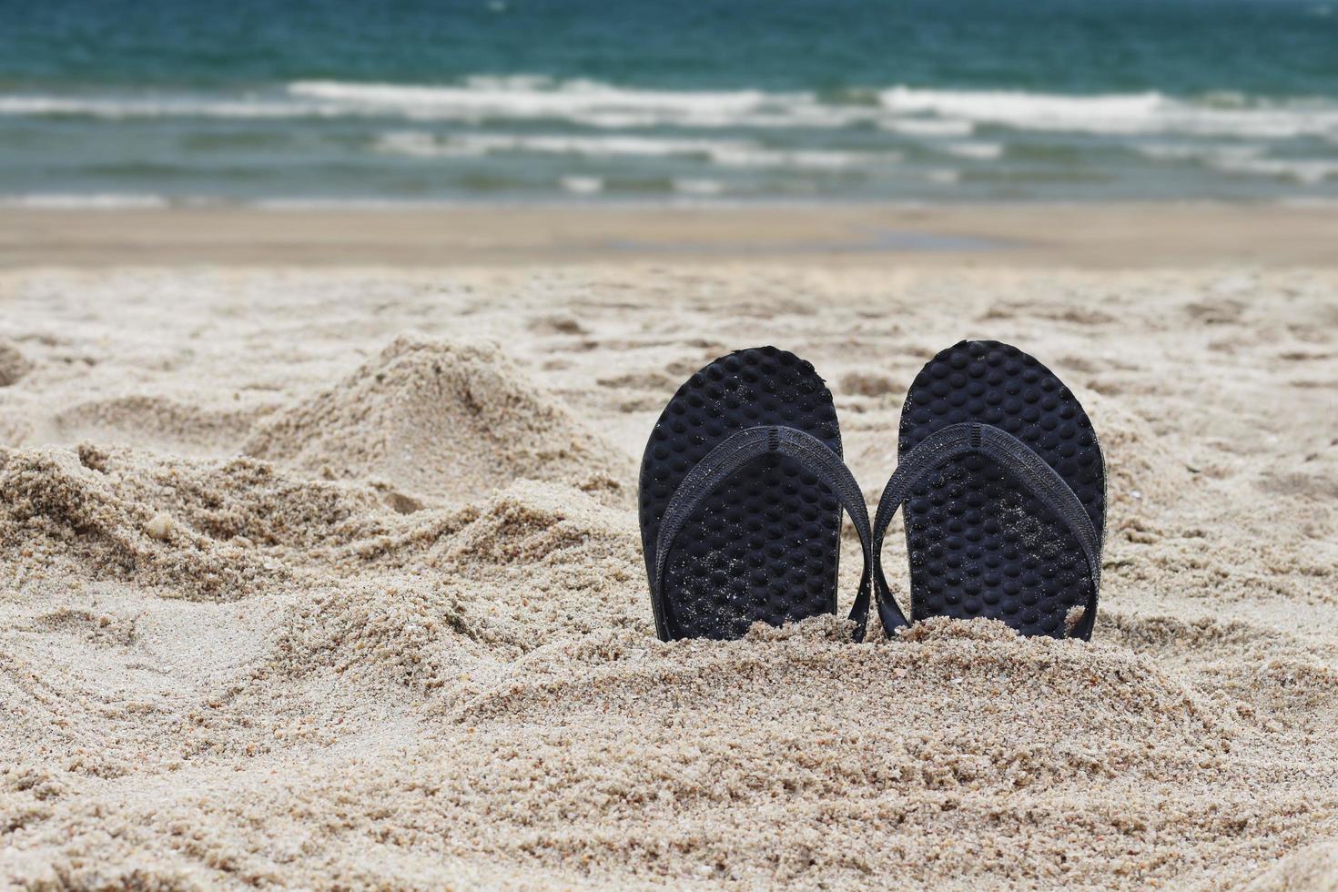 chanclas en la playa. zapatillas incrustadas en la playa de arena. foto