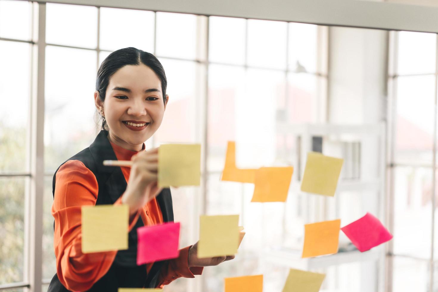 Business asian woman use message paper stick on glass board with window light. photo