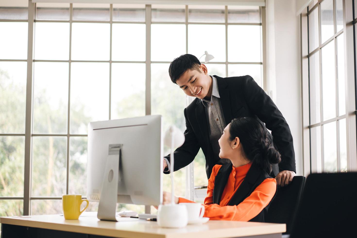 Young adult asian business man teaching work to woman in office on day photo