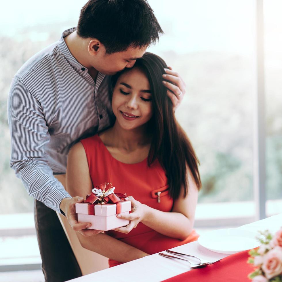 hombre pareja mano sostenga una caja de regalo roja presente romántica dársela a la novia. foto