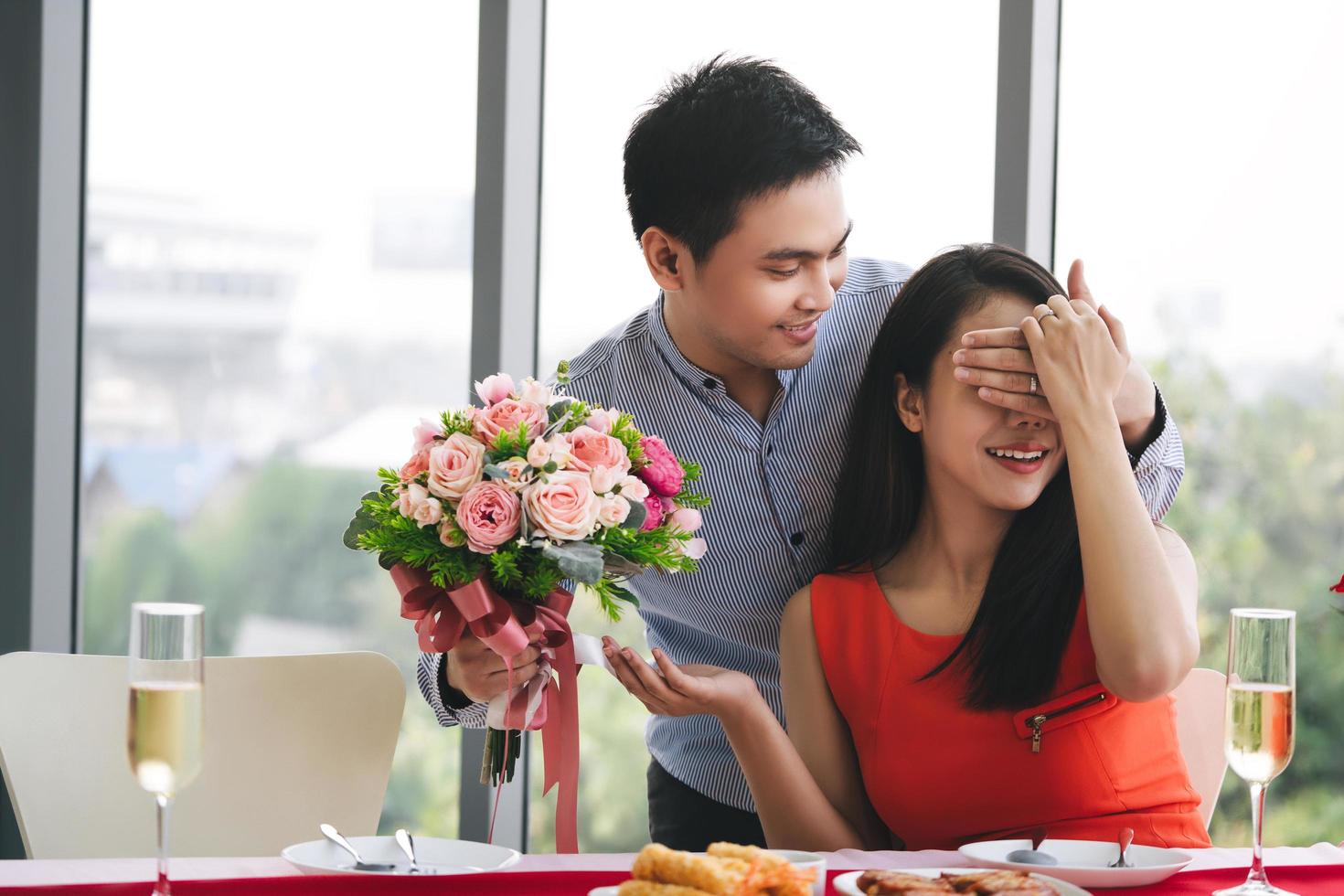 Lover with surpise flower bouquet at dinner table. photo