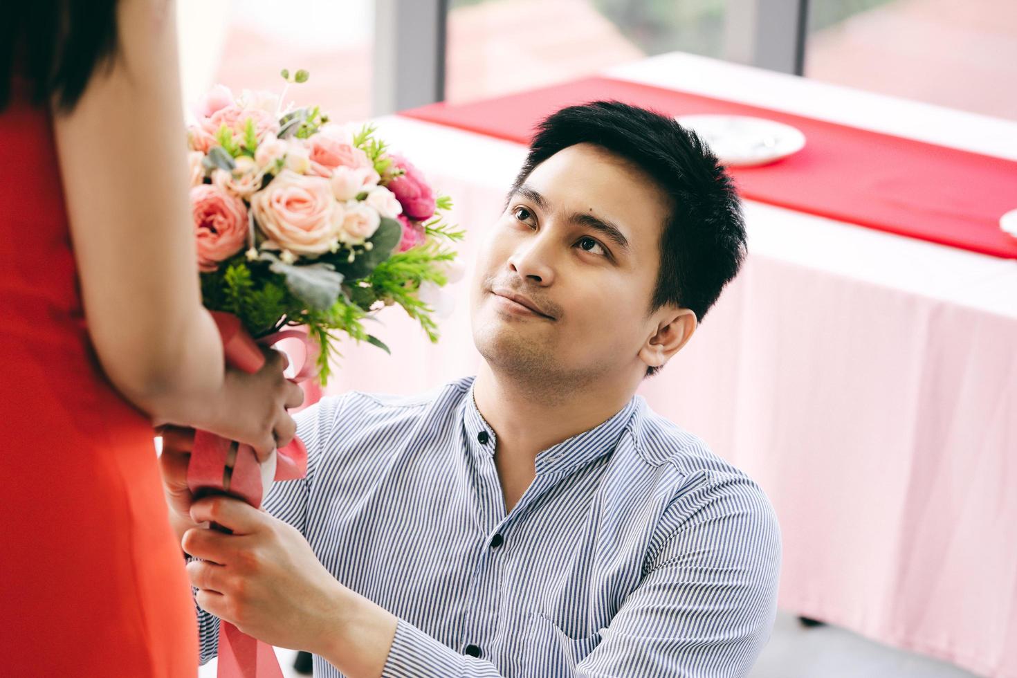 pareja asiática con ramo de flores en la mesa de la cena en el aniversario. foto