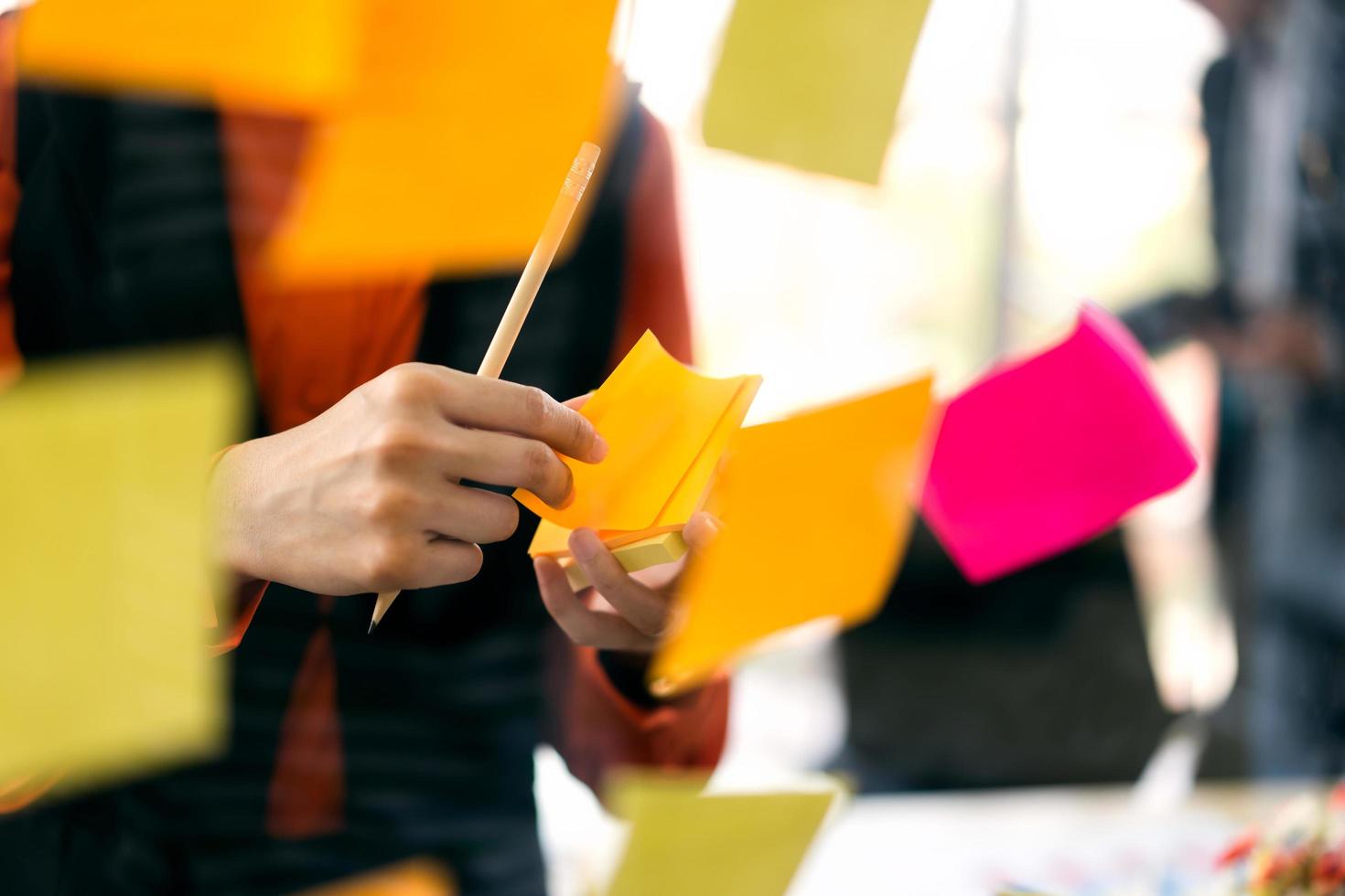 Adult business woman use a post it for stick on a glass board. photo