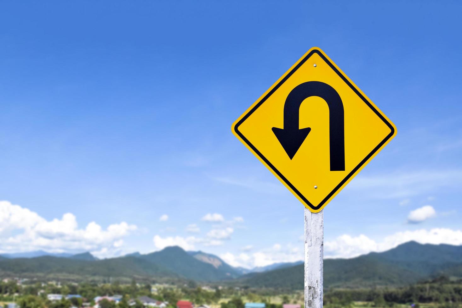 Left turn sign on white pole with clouds and blue sky background. photo