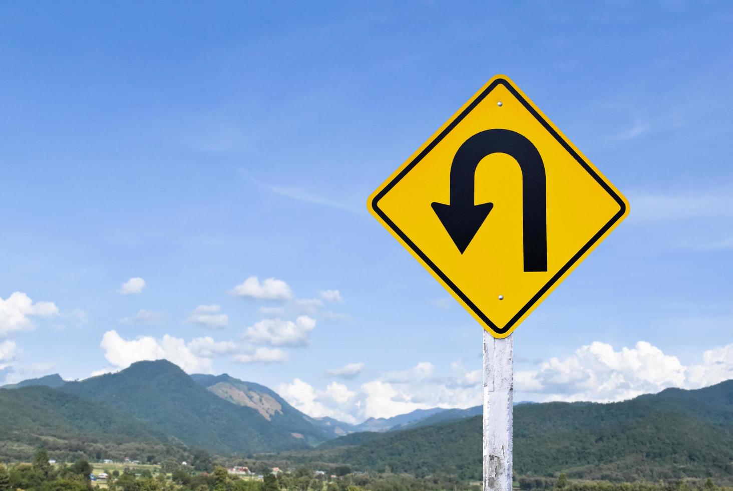 Left turn sign on white pole with clouds and blue sky background. photo