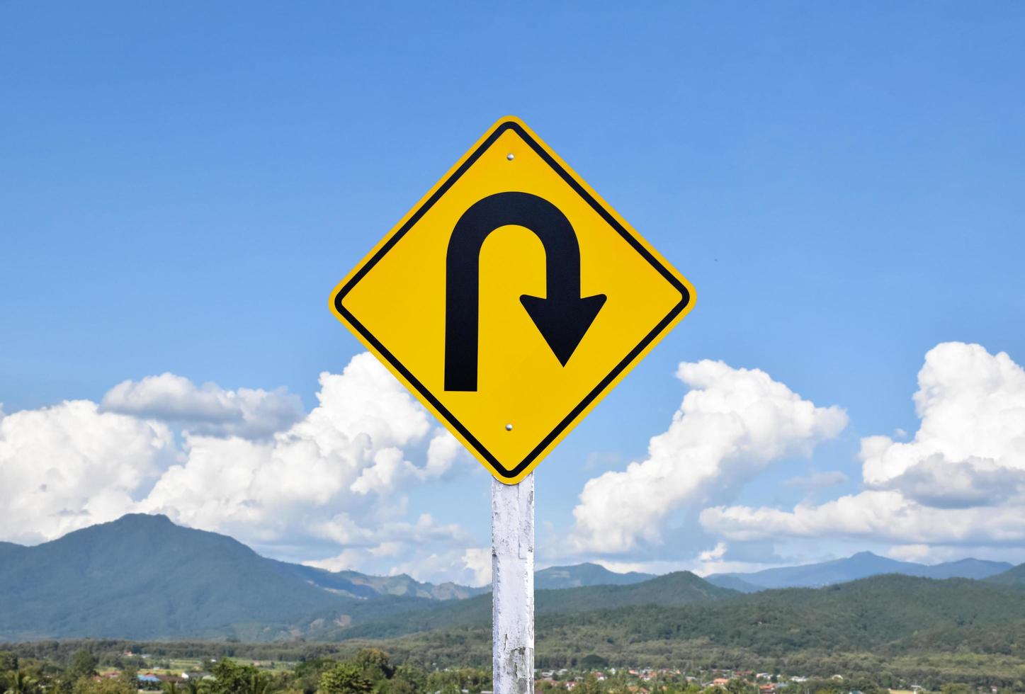 Right turn sign on white pole with clouds and blue sky background. photo