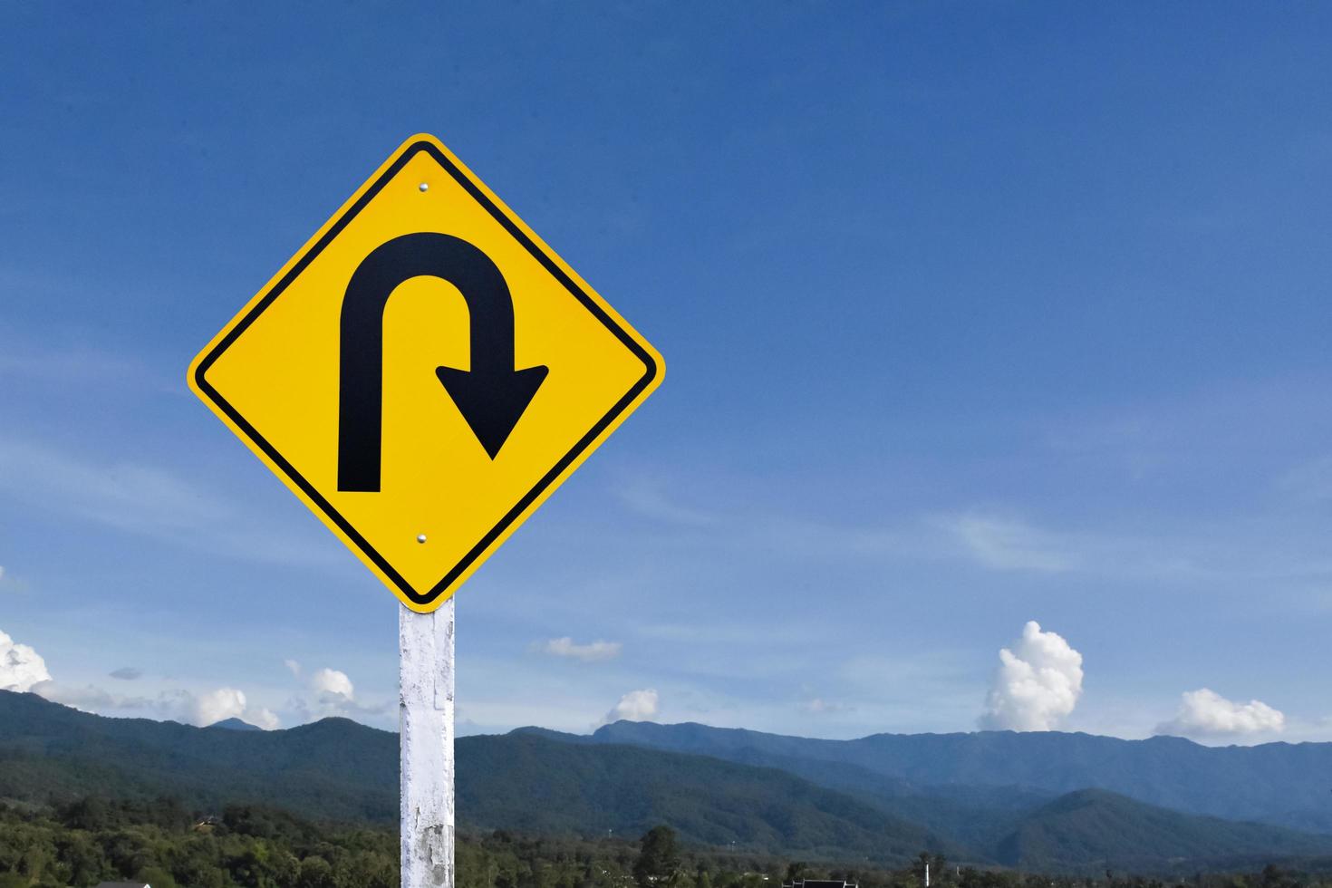 Right turn sign on white pole with clouds and blue sky background. photo