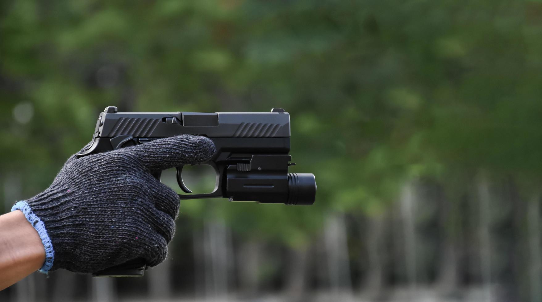 9mm automatic pistol which added troch under the muzzle holding in hand, copy space, soft and selective focus on pistol. photo