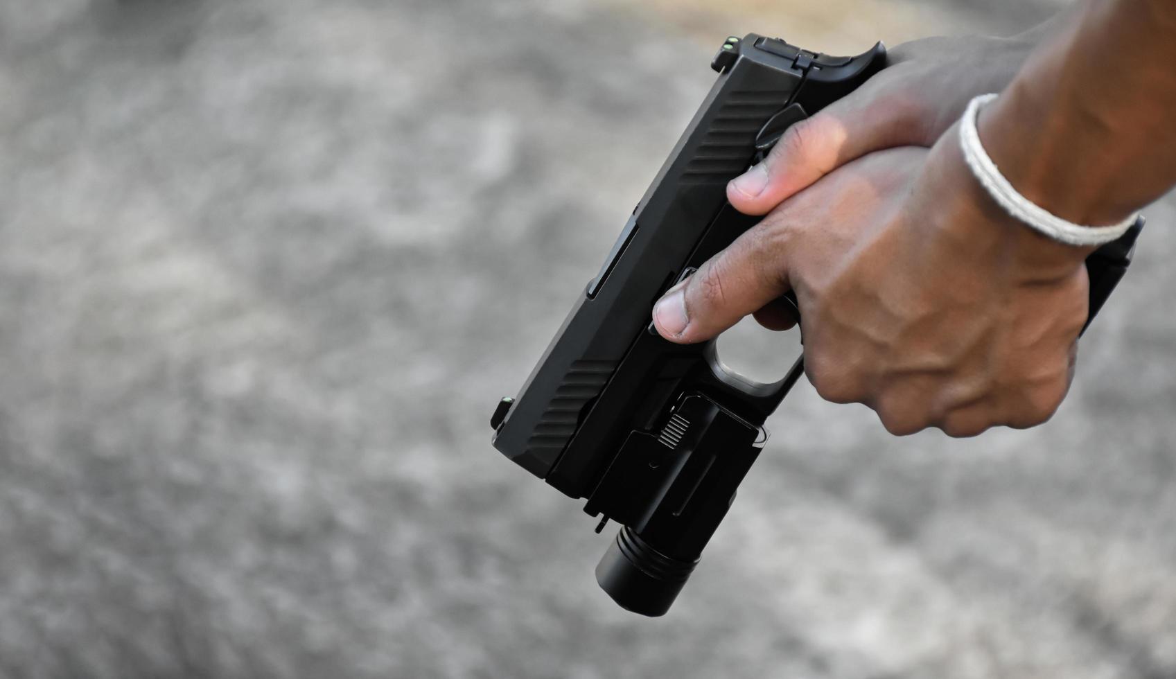 Pistola automática de 9 mm que agregó troch debajo del bozal sosteniendo en la mano, espacio de copia, enfoque suave y selectivo en la pistola. foto