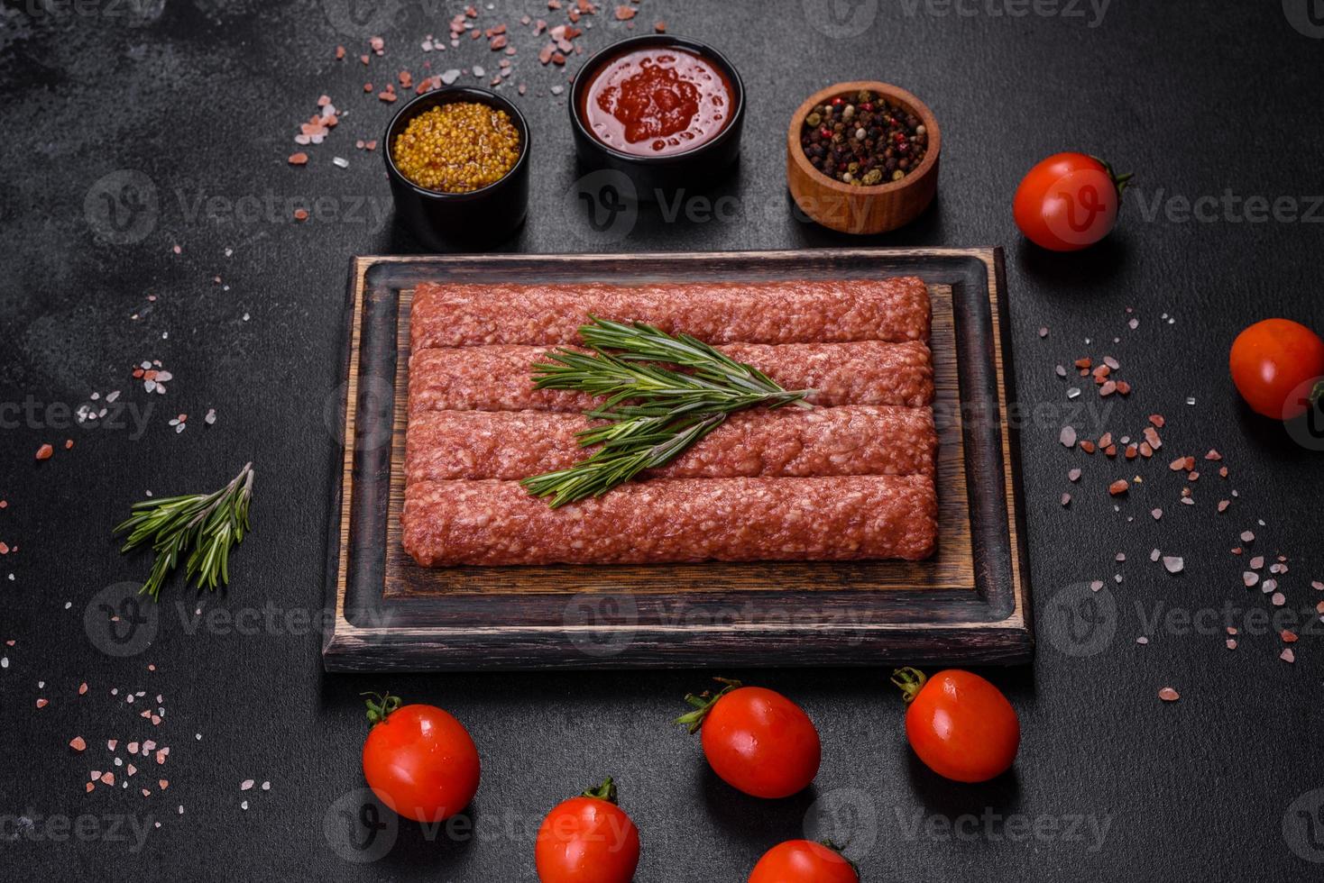 Fresh raw mince for grilled kebab with spices and herbs on a dark concrete background photo