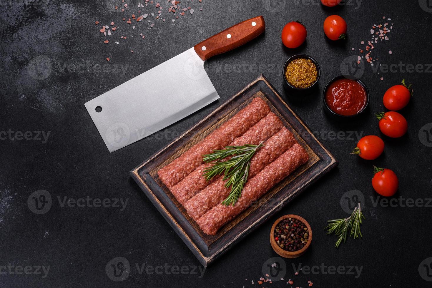 carne picada fresca cruda para kebab a la parrilla con especias y hierbas sobre un fondo de hormigón oscuro foto