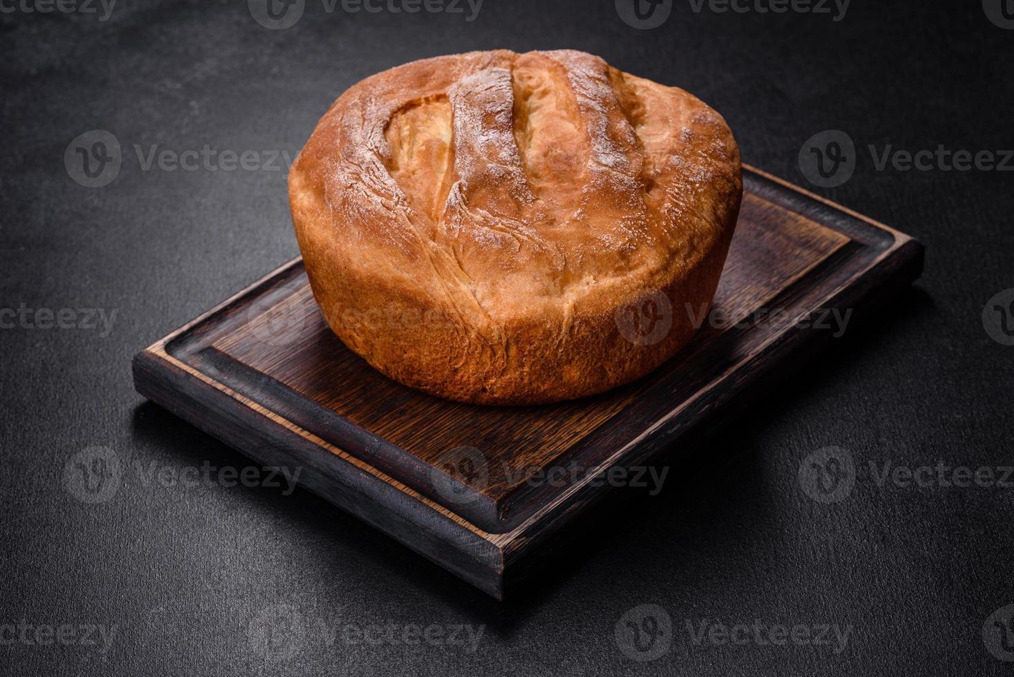 sabroso pan blanco recién horneado en horno sobre un fondo de hormigón oscuro foto