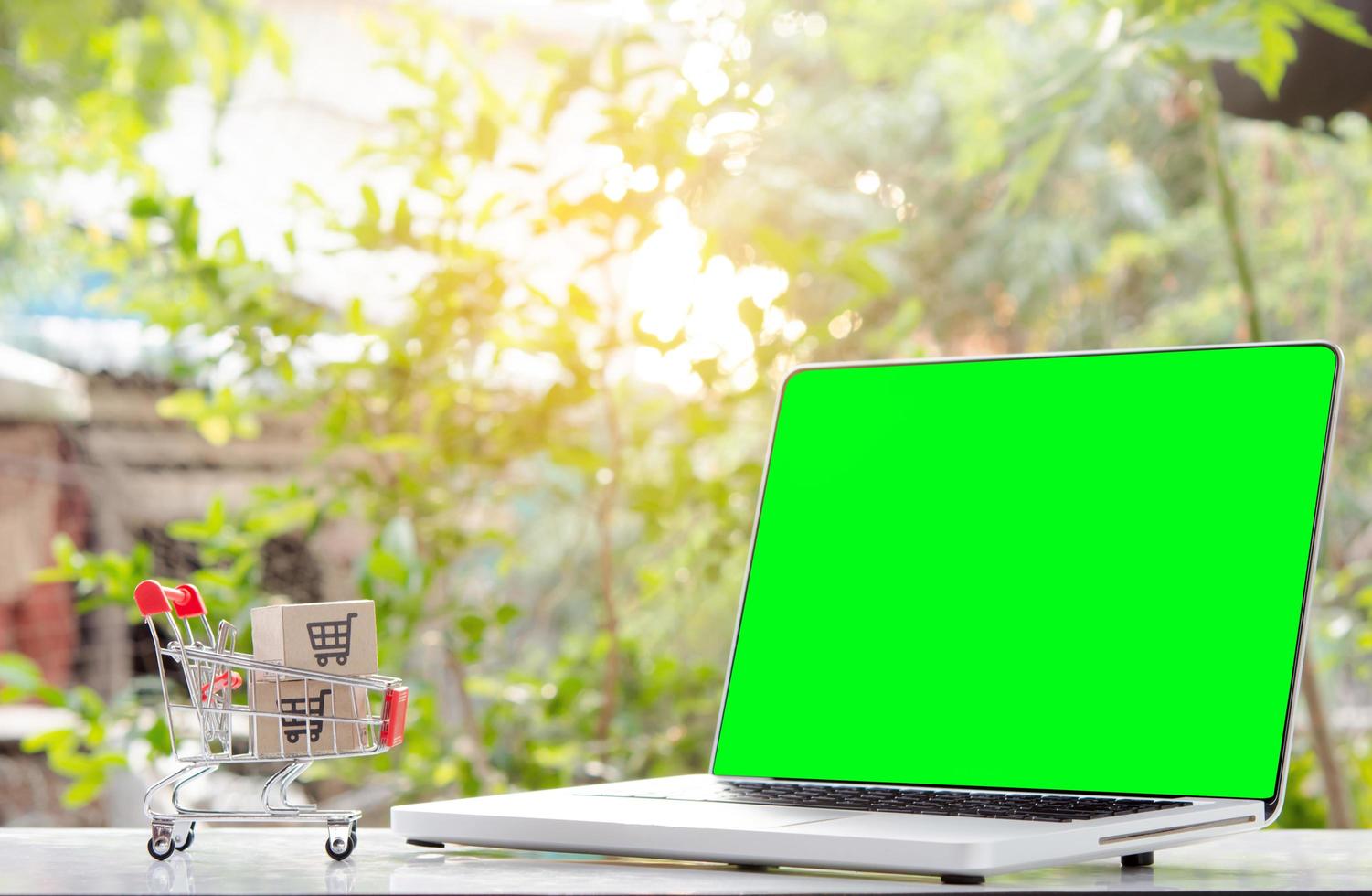Shopping online. cardboard box with a shopping cart logo in a trolley and laptop green screen . Shopping service on The online web. offers home delivery photo