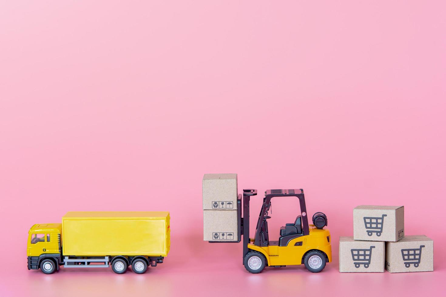 Logistics, and delivery service - Cargo truck, Forklift and paper cartons or parcel with a shopping cart logo on Pink background. Shopping service on The online web and offers home delivery. photo