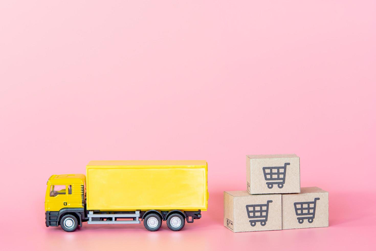 Logistics, and delivery service - Cargo truck and paper cartons or parcel with a shopping cart logo on Pink background. Shopping service on The online web and offers home delivery. photo