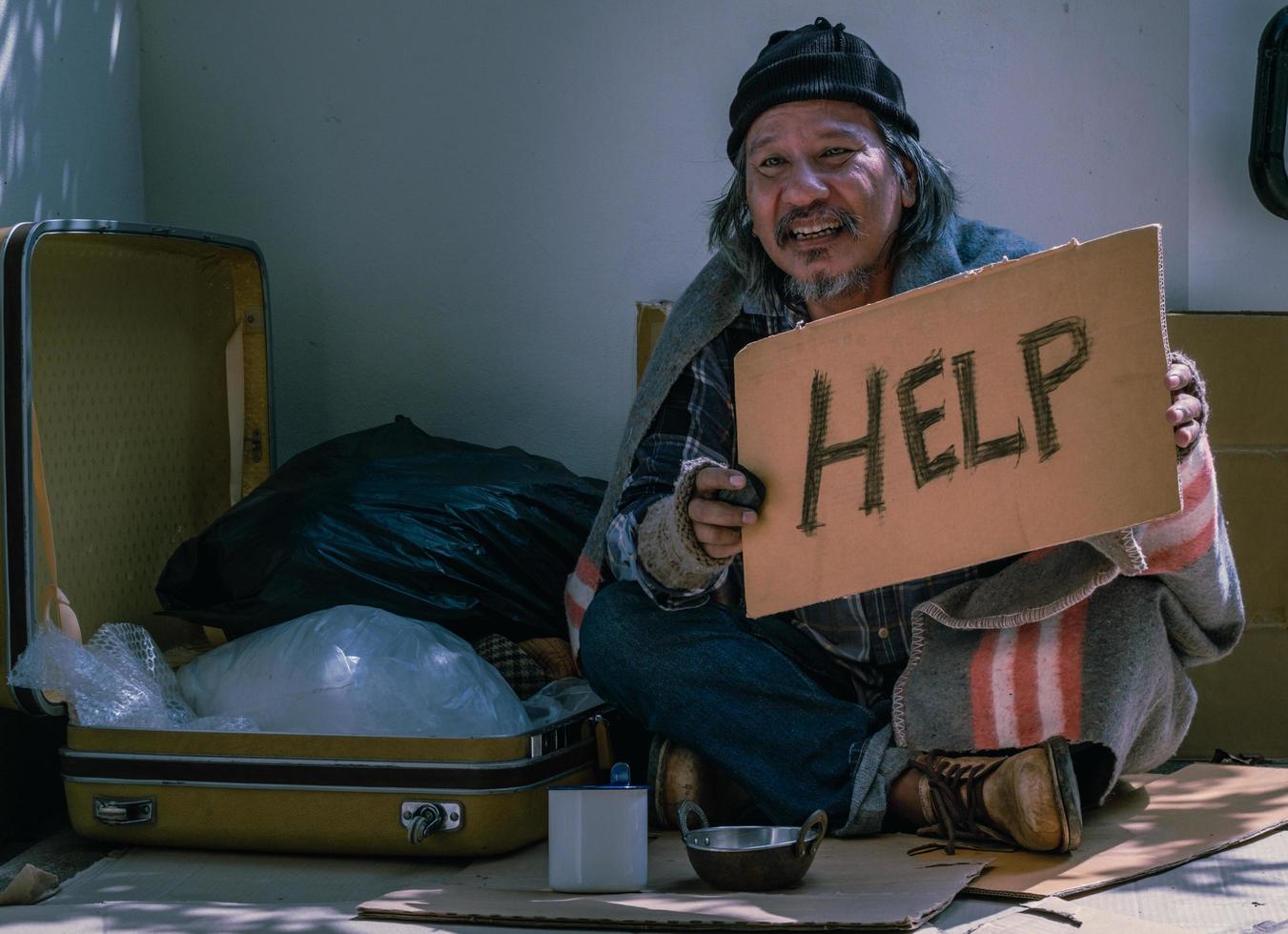 hombre sin hogar pide ayuda y compartir. muchas personas se enfrentan a personas sin trabajo y sin hogar después de la epidemia de covid 19. este hombre tiene que vivir en la vereda y pide ayuda.. foto