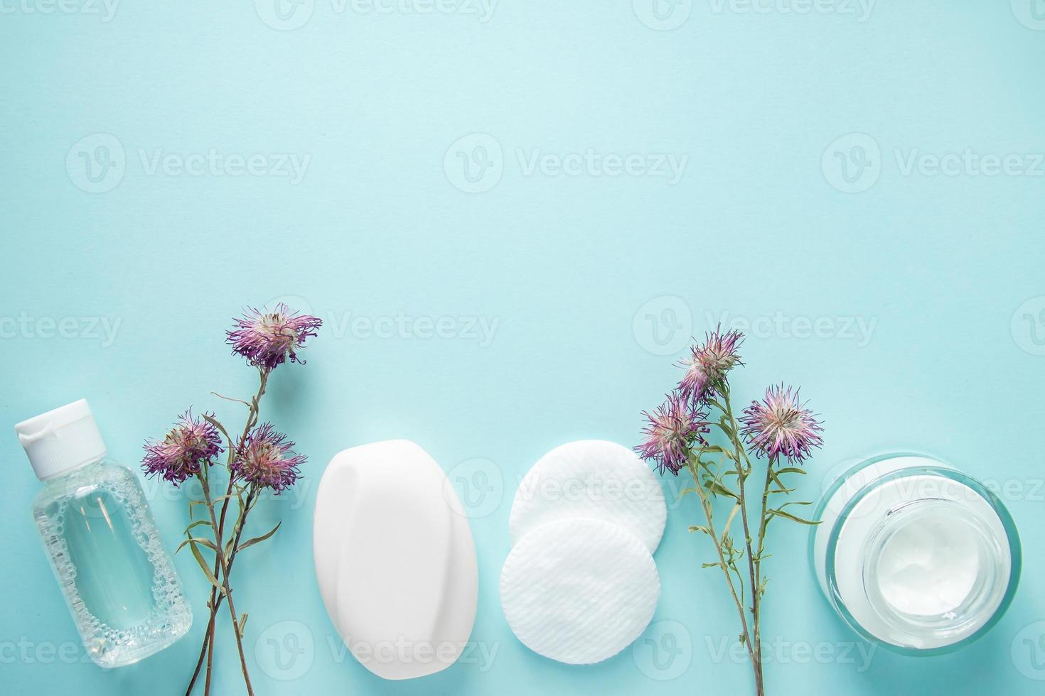 Cosmetic products and dry flowers on blue background. photo