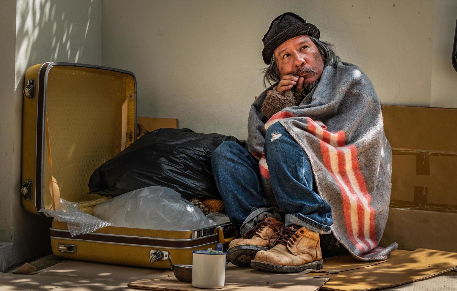 Homeless man waits for any help and donation from passer by. photo