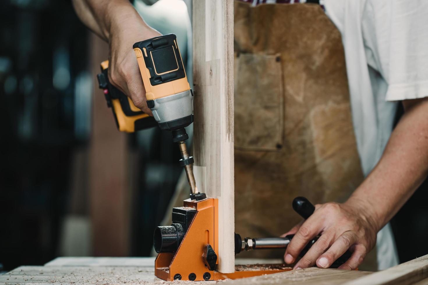 carpenter use drill bit and centering dowel jig or pocket hole jig tool to make strong joints on wooden plate. woodworking concept.selective focus. photo