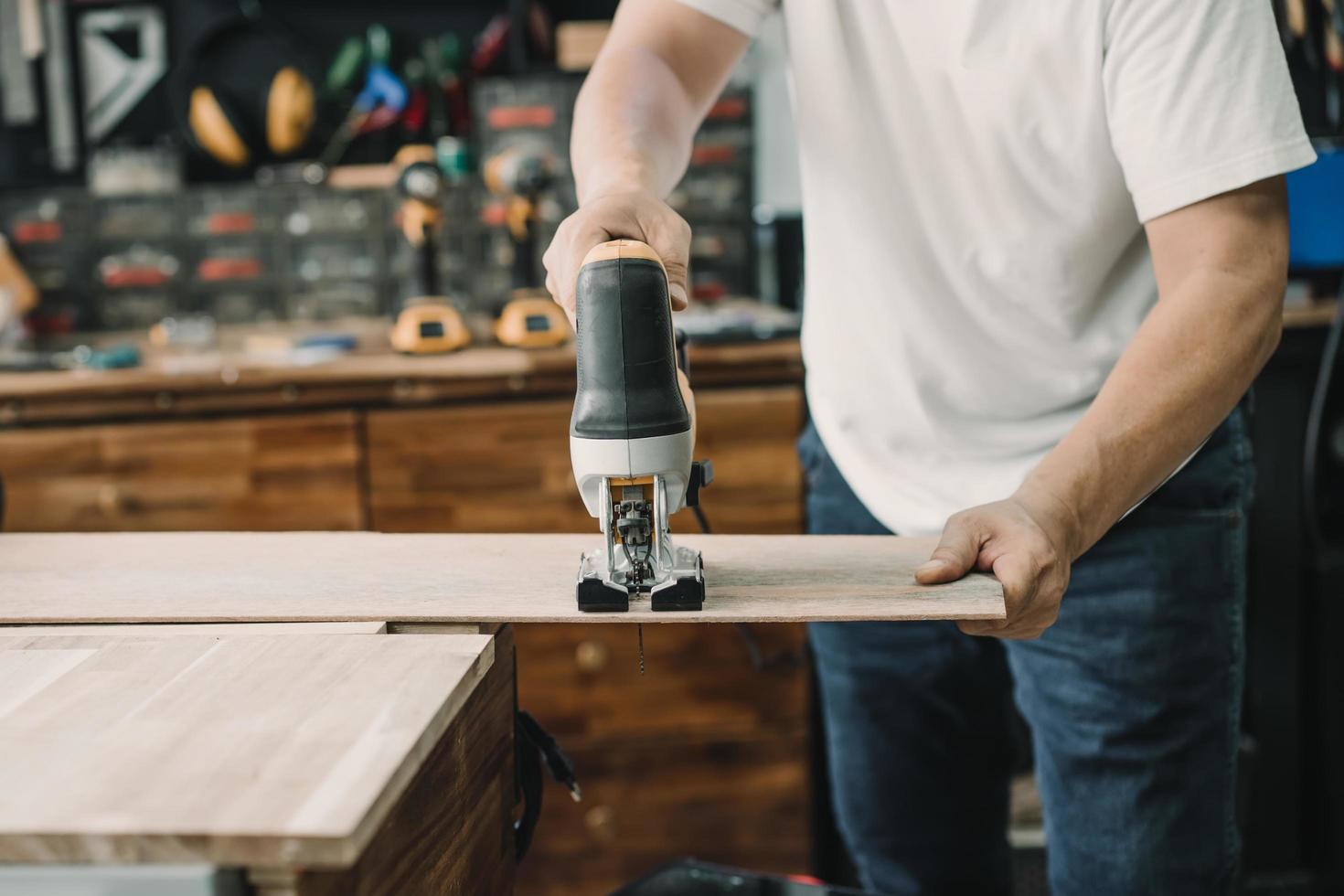 carpintero cortando madera con sierra eléctrica en taller, concepto de carpintería, enfoque selectivo foto