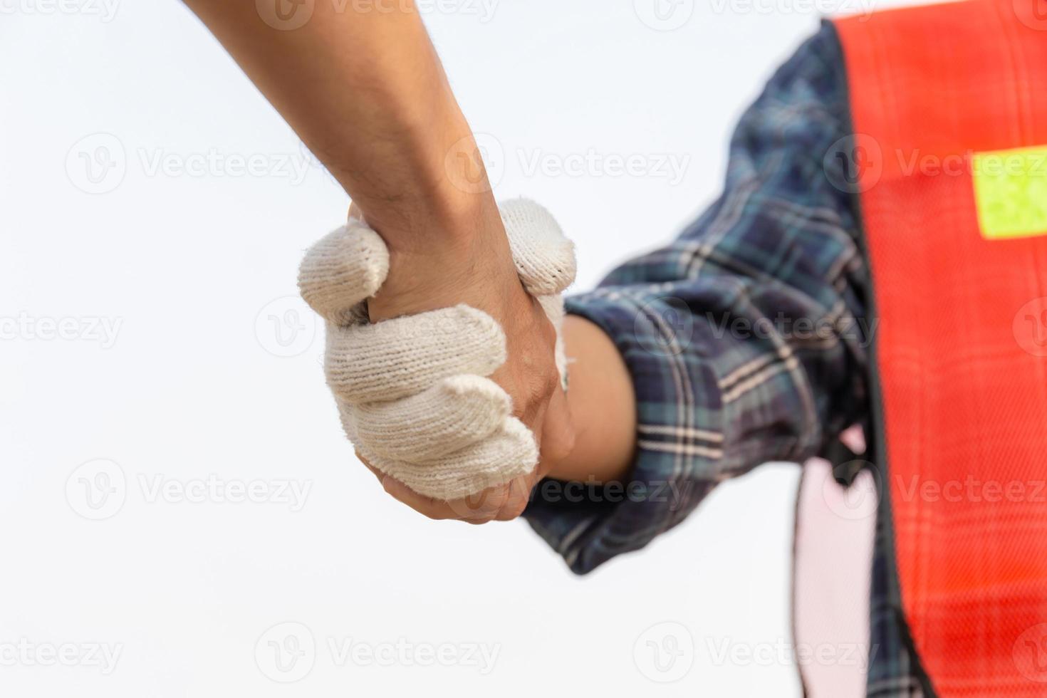 Close up of engineer and worker handshake with blurred construction site, Success and Teamwork concept photo