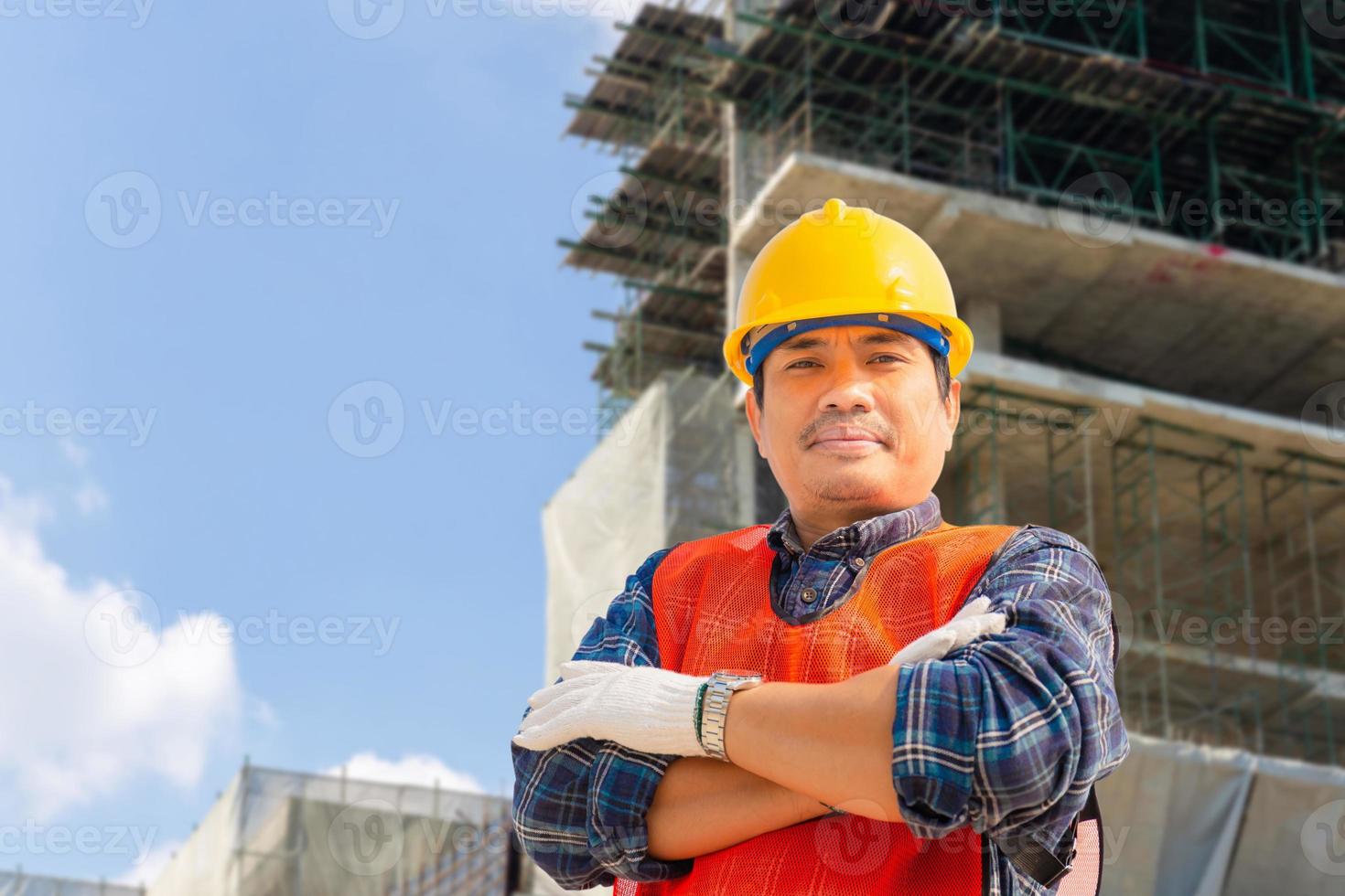 ingeniero trabajador con ruta de recorte revisando y planificando proyecto en el sitio de construcción, hombre sonriente sobre fondo borroso foto