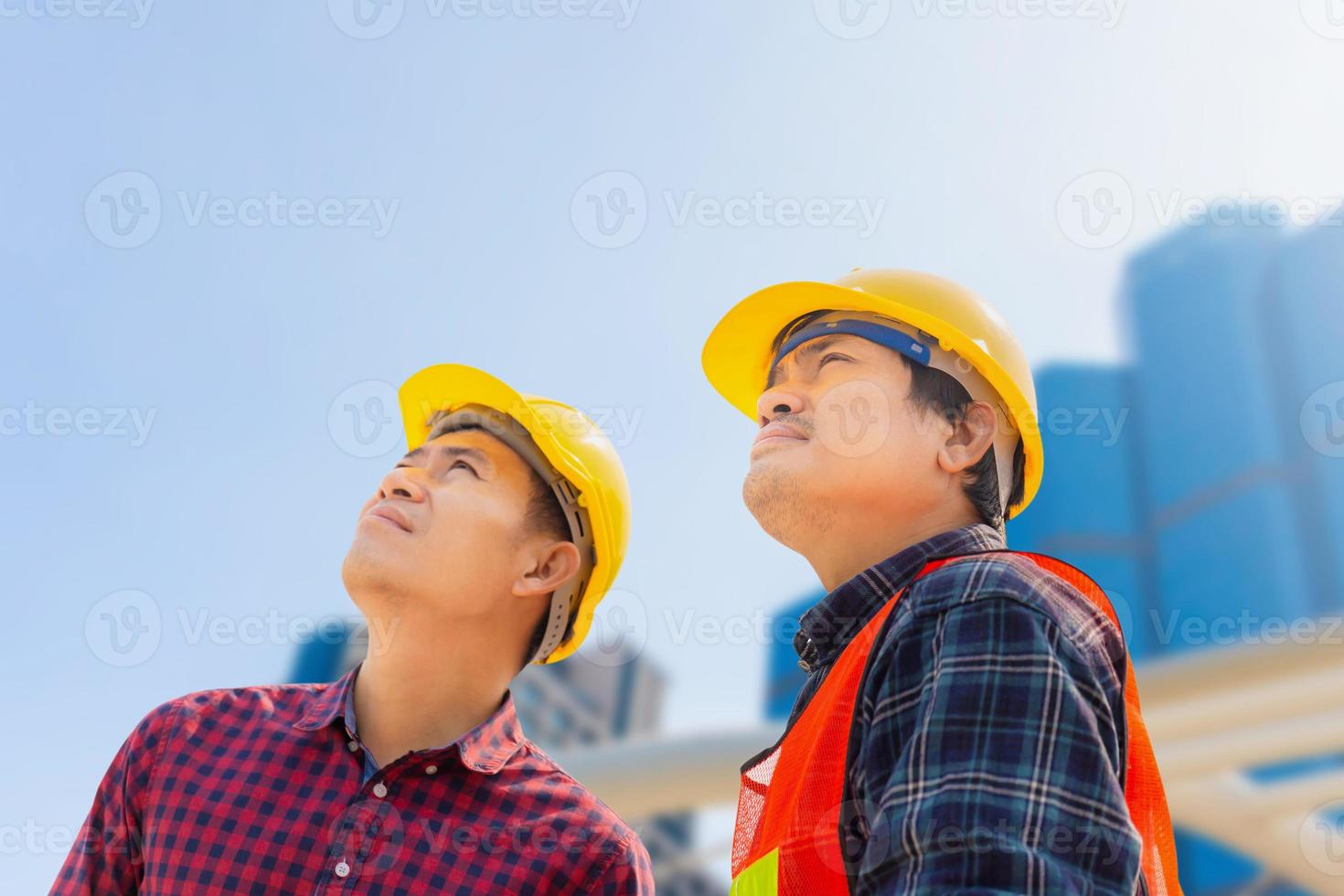 ingeniero y trabajador con un proyecto de comprobación y planificación de rutas de recorte en el sitio de construcción, hombre mirando al cielo sobre un fondo borroso foto