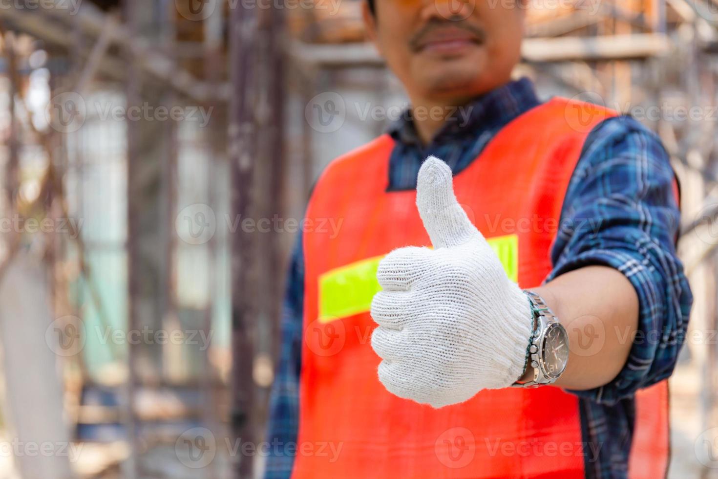 ingeniero trabajador mano dando pulgar hacia arriba sobre el sitio de construcción borroso, concepto exitoso foto