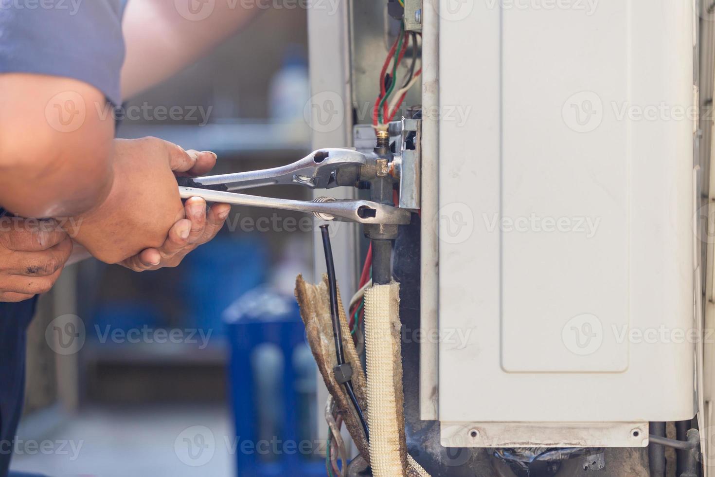hombre técnico usando una llave que fija el concepto moderno de sistema de aire acondicionado, mantenimiento y reparación foto