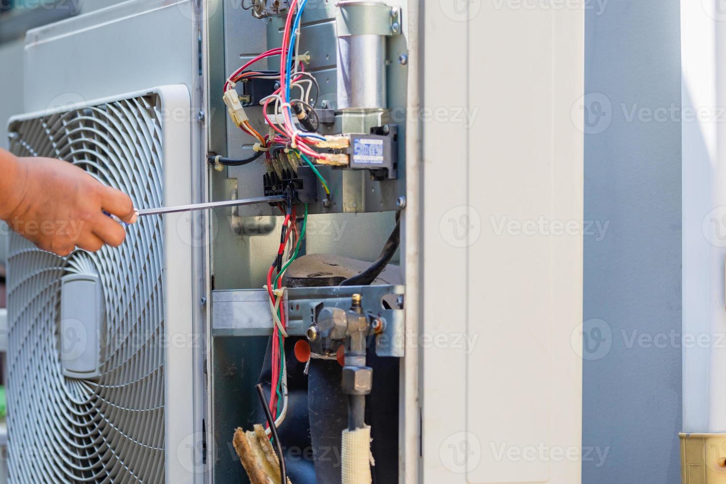 Male technician hands using a screwdriver fixing modern air conditioner, repairing and servicing, Maintenance and repairing concept photo