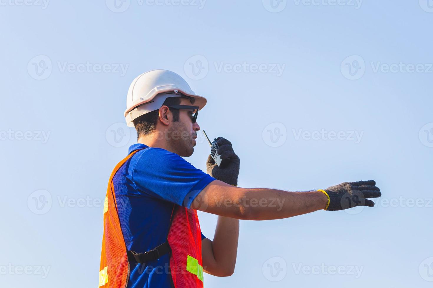 Foreman worker in hardhat and safety vest talks on two-way radio control loading containers box from cargo photo