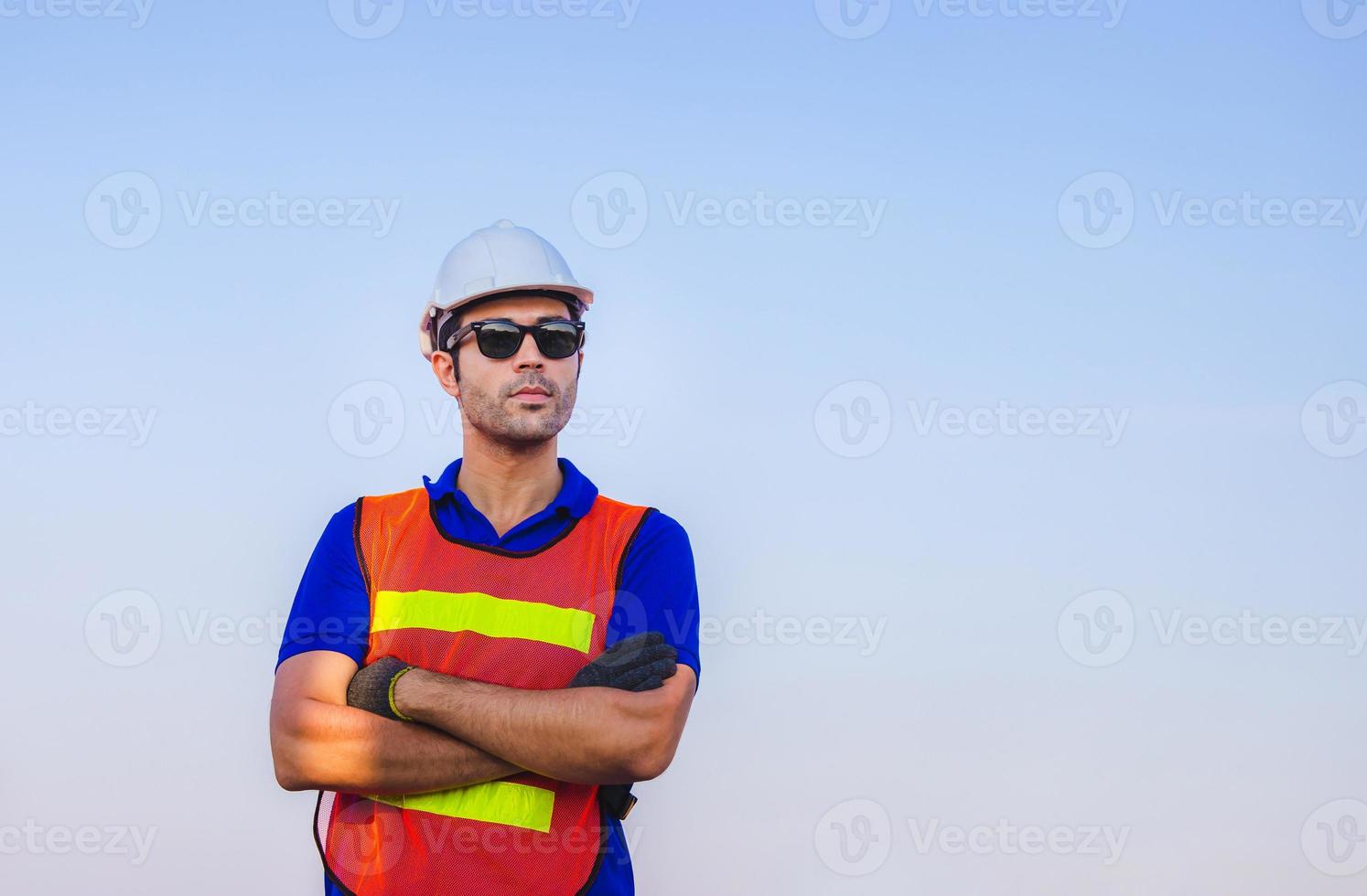 Cheerful factory worker man in hard hat smiling with arms crossed as sign of Success photo