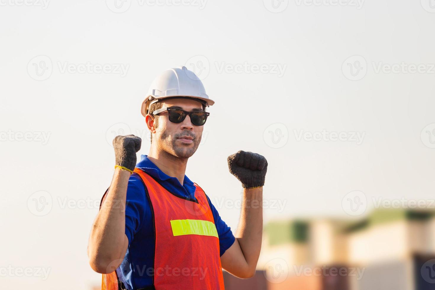 Factory worker man in hard hat with celebrating victory, young man celebrates with two hand in the air photo