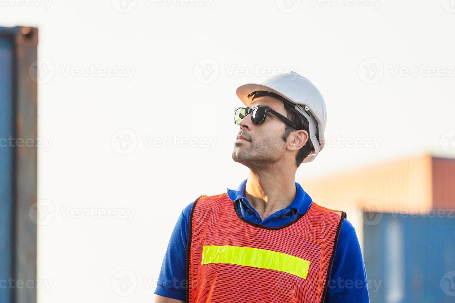 trabajador con casco y chaleco de seguridad parado en contenedores de carga, ingeniero revisando la caja de contenedores de la carga foto