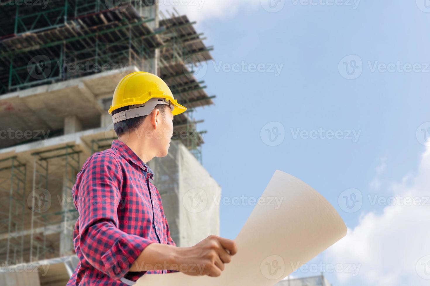 hombre ingeniero con proyecto de control y planificación de ruta de recorte en el sitio de construcción, hombre sosteniendo un plano y mirando hacia el cielo foto