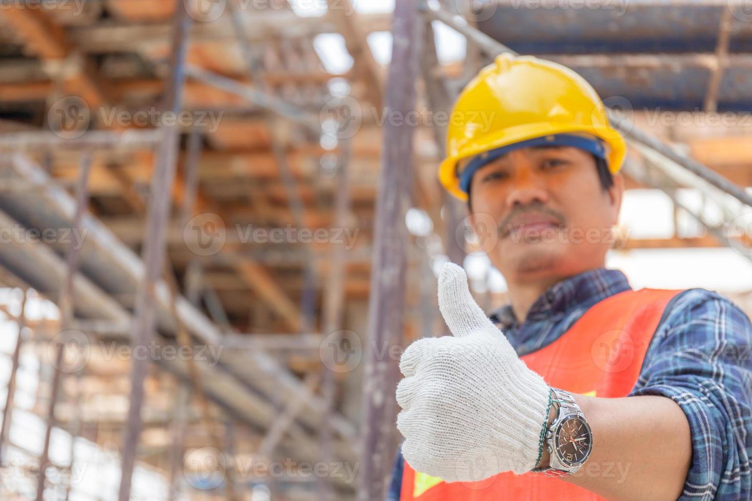 Engineer worker man hand giving thumb up over blurred construction site, Successful concept photo